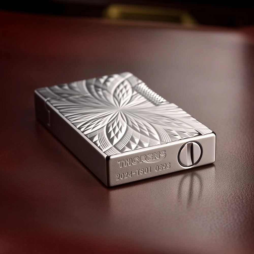 A close-up view of the Thorens Blooming Radiance silver lighter lying on its side, highlighting the polished finish, deep geometric engravings, and the branded bottom plate with its serial number.