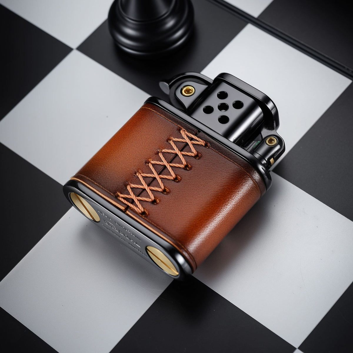 Thorens handmade cowhide lighter in brown and black shown from the back, highlighting leather lacing, black top assembly, and brass base screws.