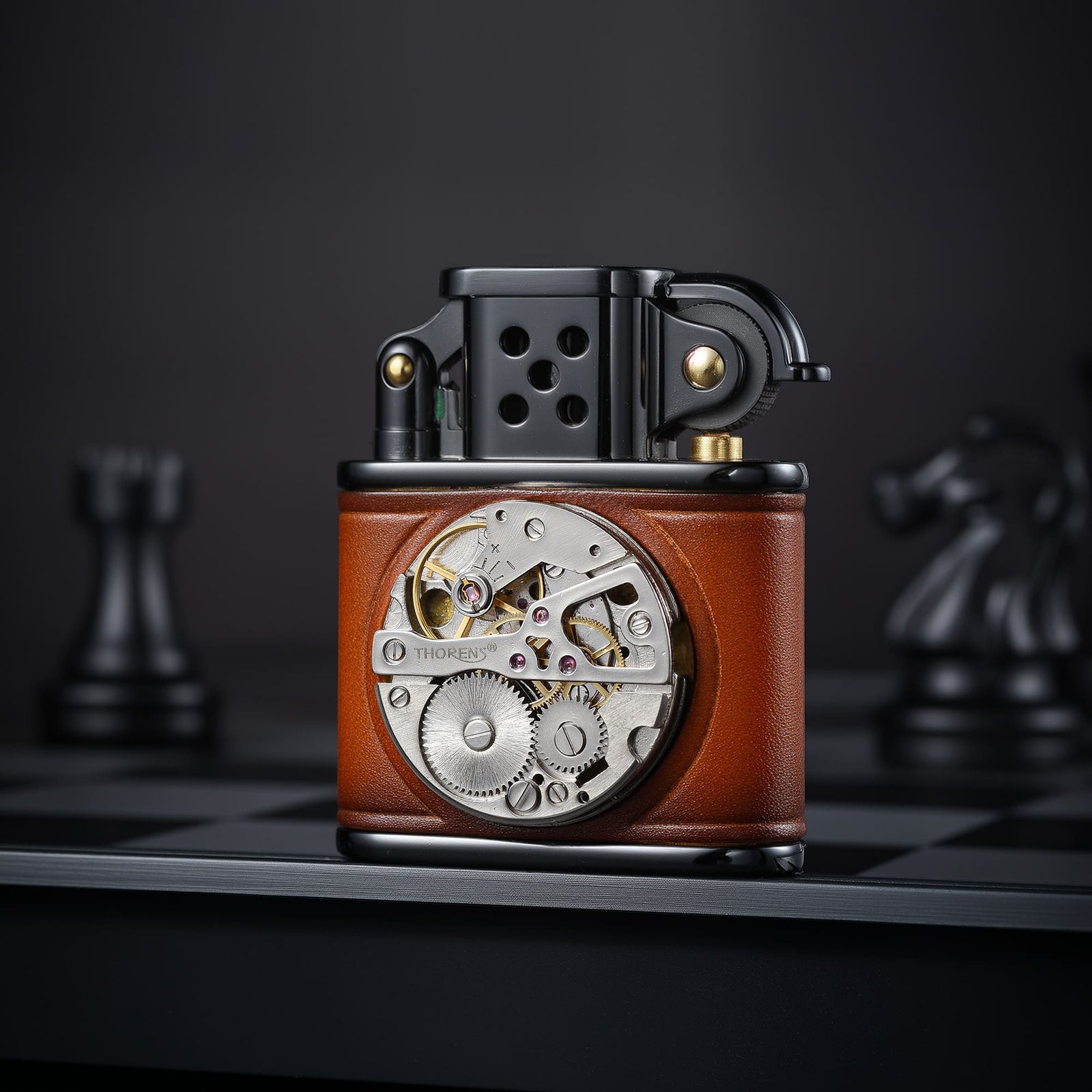 Thorens handmade cowhide lighter in brown and black shown front-facing, highlighting the inlaid mechanical movement dial and black metal top assembly.