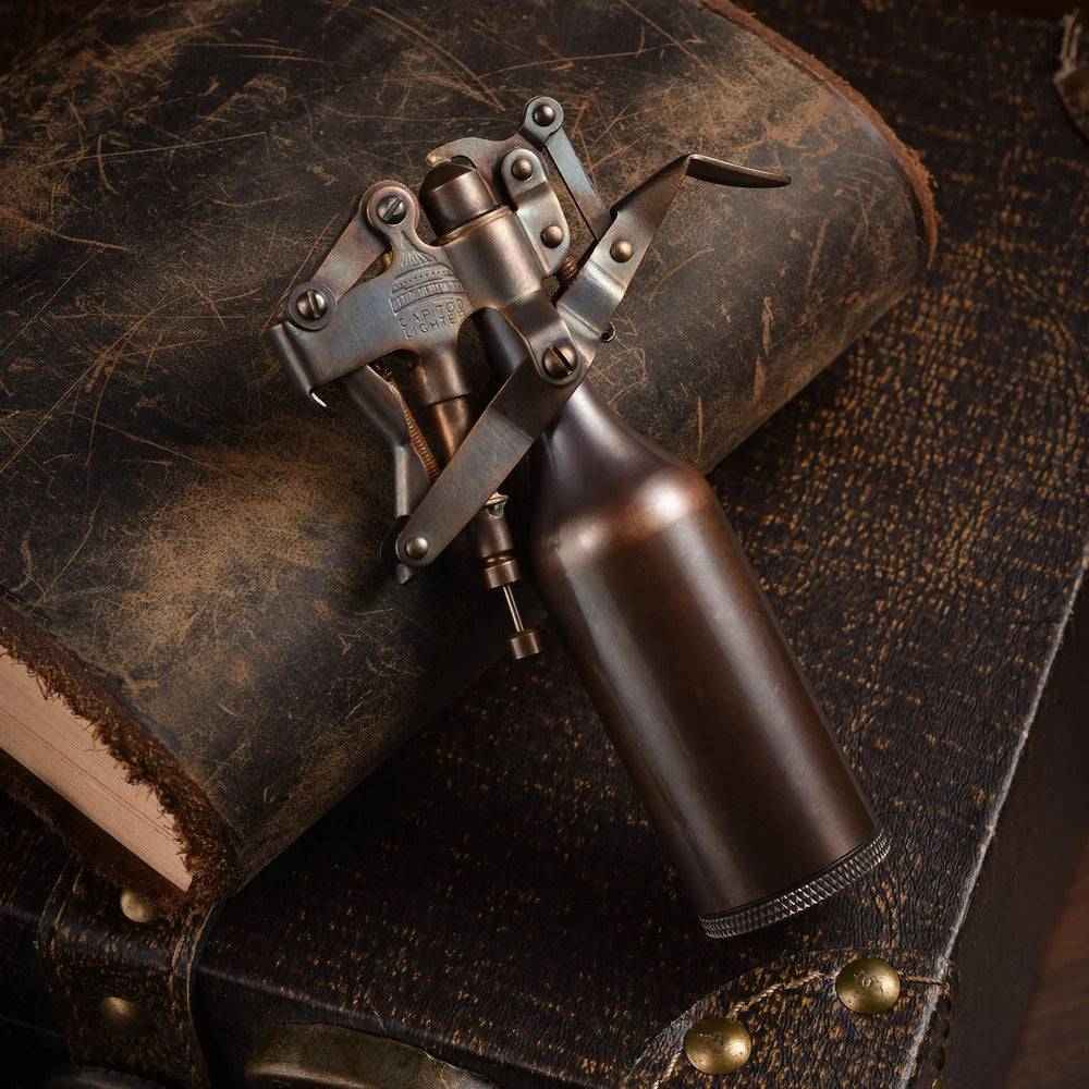 A Capitol Table Lighter with a glossy antique finish and intricate mechanical levers, resting on a weathered leather book to highlight its heritage craftsmanship.