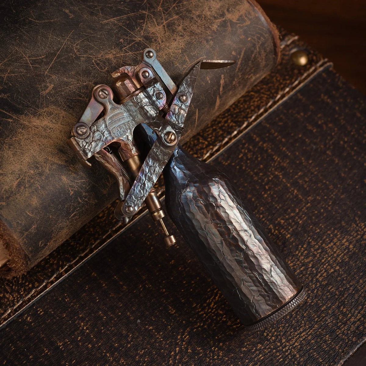 A Capitol Table Lighter featuring unique hand-carved crack patterns on a weathered brass body, resting on a leather-textured surface to highlight its artisan craftsmanship.