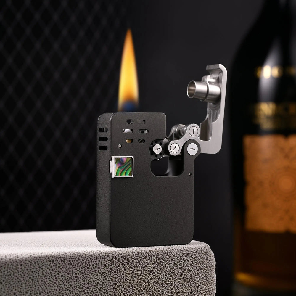 An ignited Thorens Ejection lighter in matte black, showing the unique mechanical linkage in the open position with a large, steady flame and an iridescent abalone shell inlay.