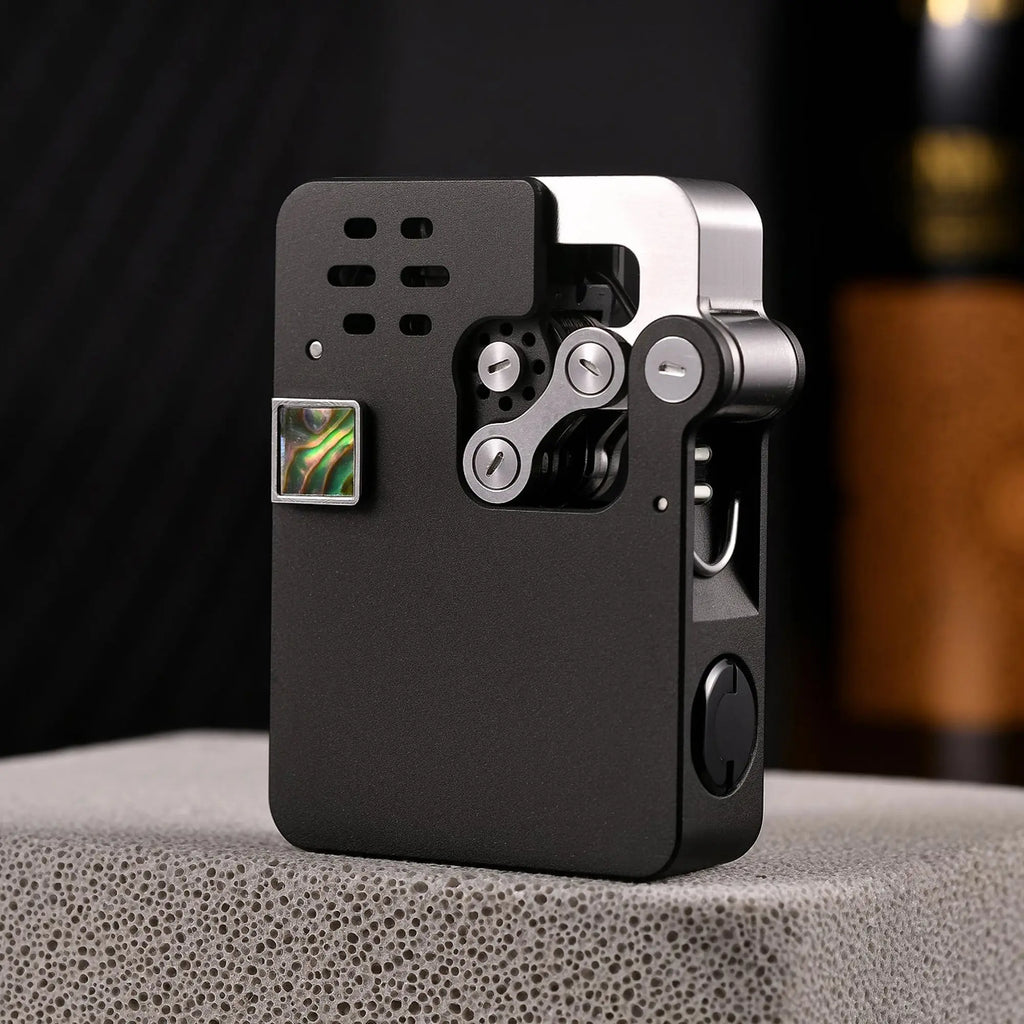 A detailed front-profile of the matte black Hollowing Machine ejection lighter, showcasing the silver mechanical linkage, iridescent abalone inlay, and precision-cut ventilation holes.