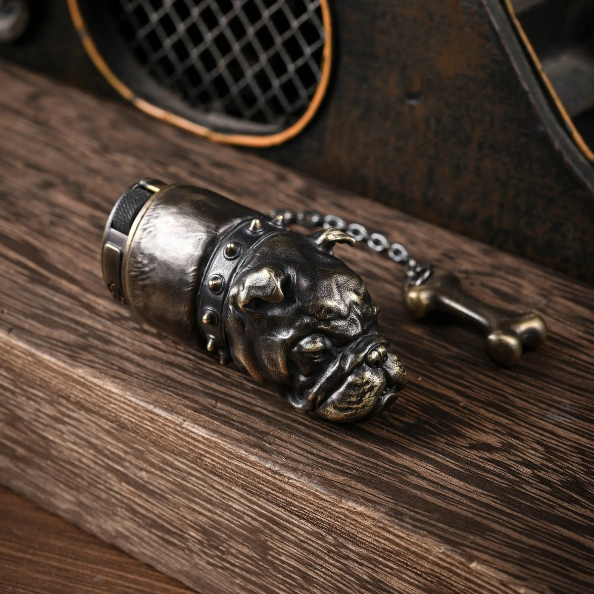 A close-up of the Thorens French Bulldog antique brass lighter resting on wood, featuring a highly detailed, sculpted dog head with a studded collar and a bone-shaped charm.