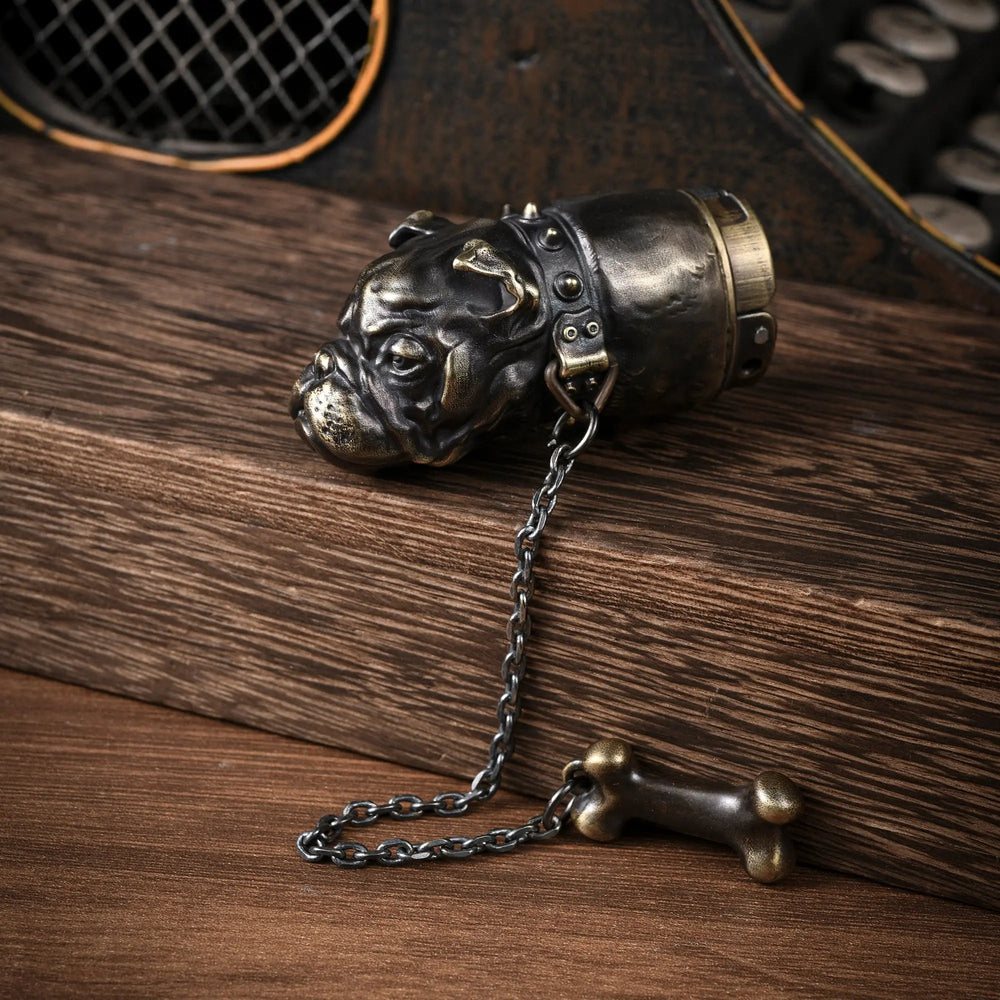 A Thorens French Bulldog lighter crafted in antique brass, showcasing the detailed bulldog head sculpture with a spiked collar and an attached bone charm on a chain.
