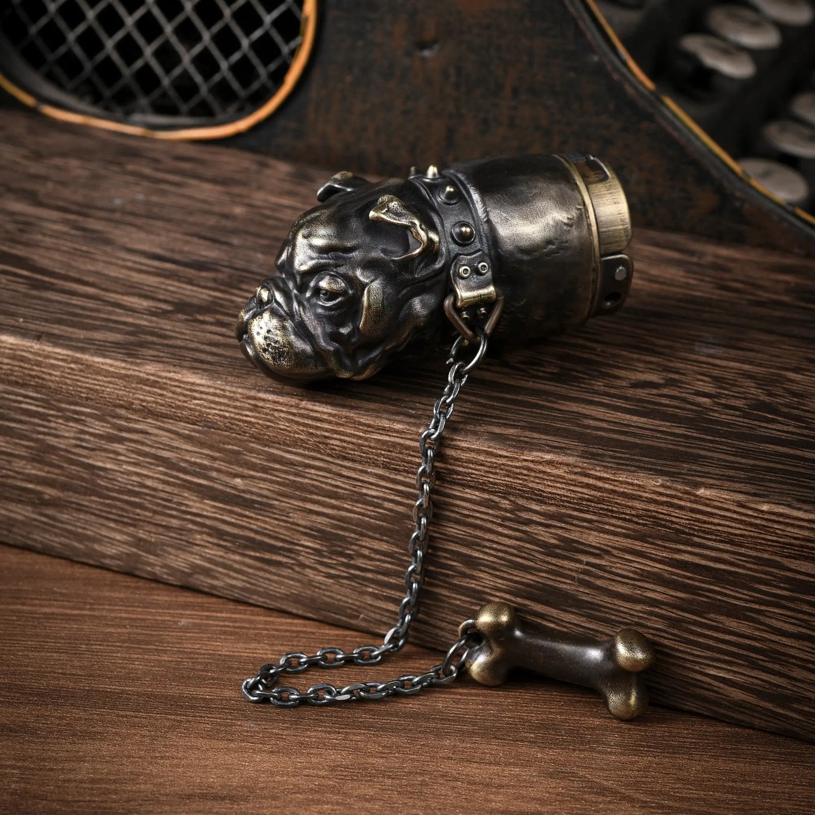 A Thorens French Bulldog lighter crafted in antique brass, showcasing the detailed bulldog head sculpture with a spiked collar and an attached bone charm on a chain.