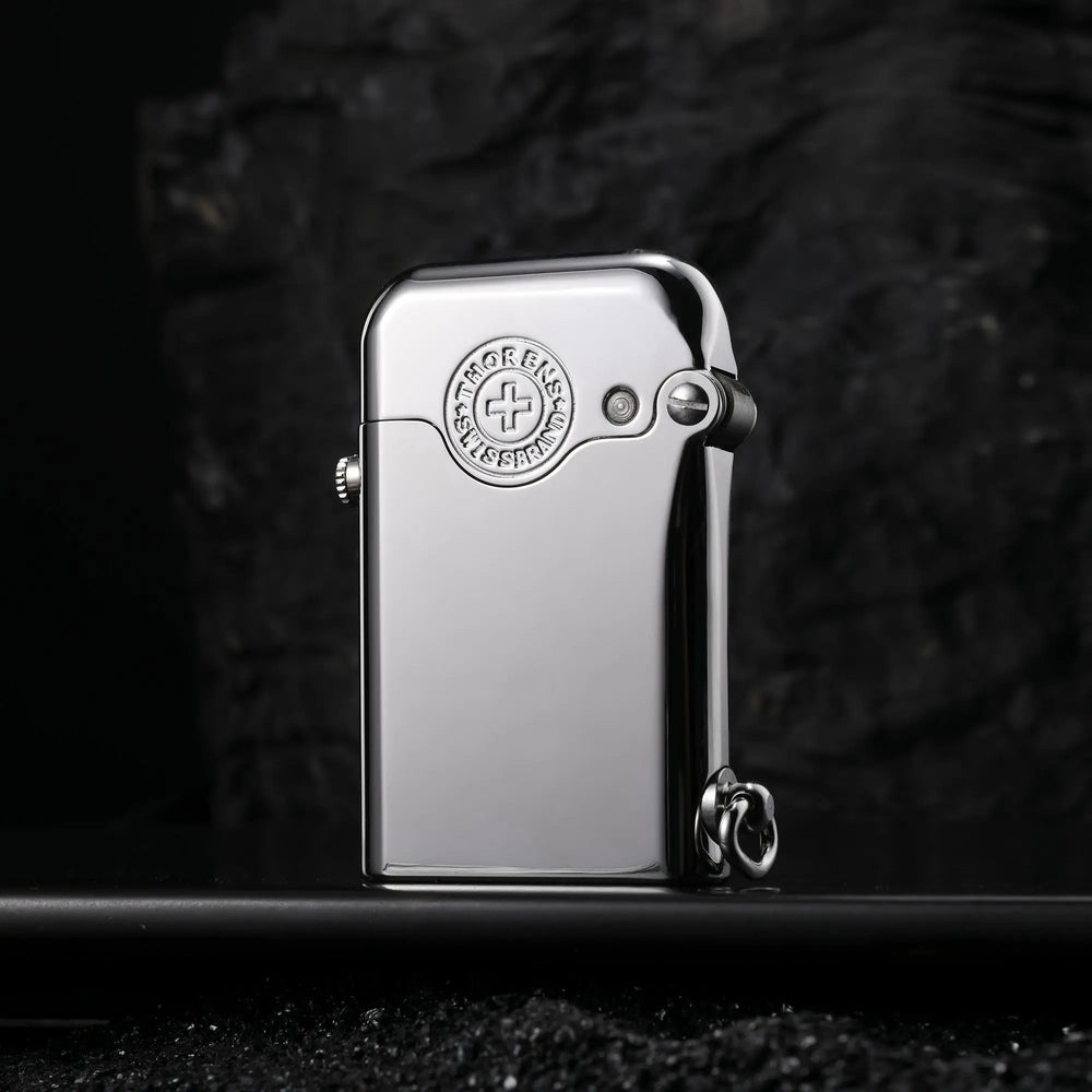 A closed Thorens Gen 1 Single Claw silver lighter featuring a high-gloss finish and a detailed Swiss heritage brand emblem, standing against a dark, textured background.