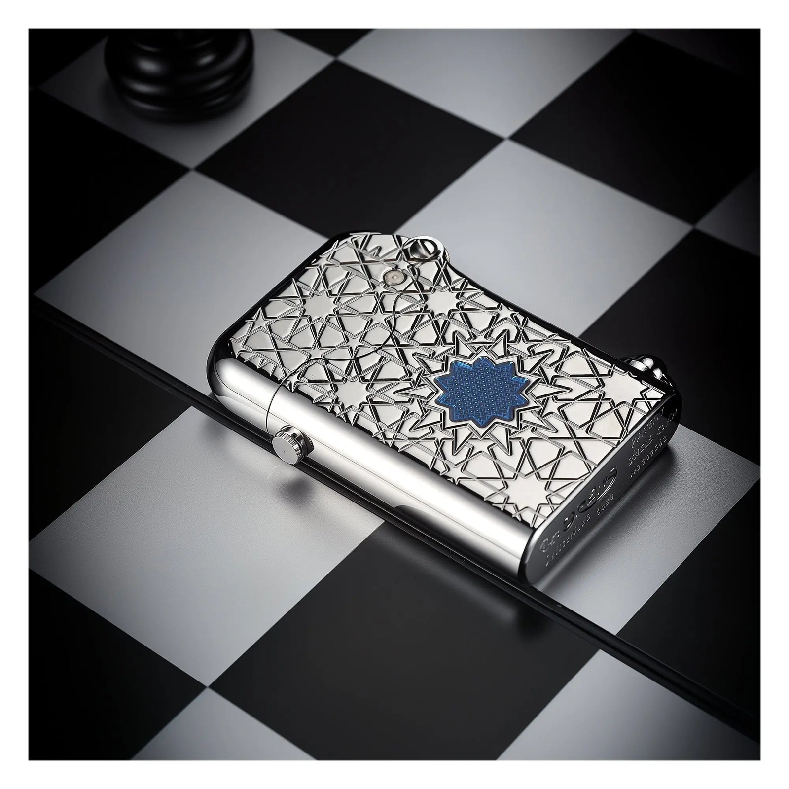 A Thorens Gen 1 Single Claw lighter featuring a silver star-patterned engraving and a vibrant blue lucky star inlay, resting elegantly on a monochrome chessboard for a refined collectible aesthetic