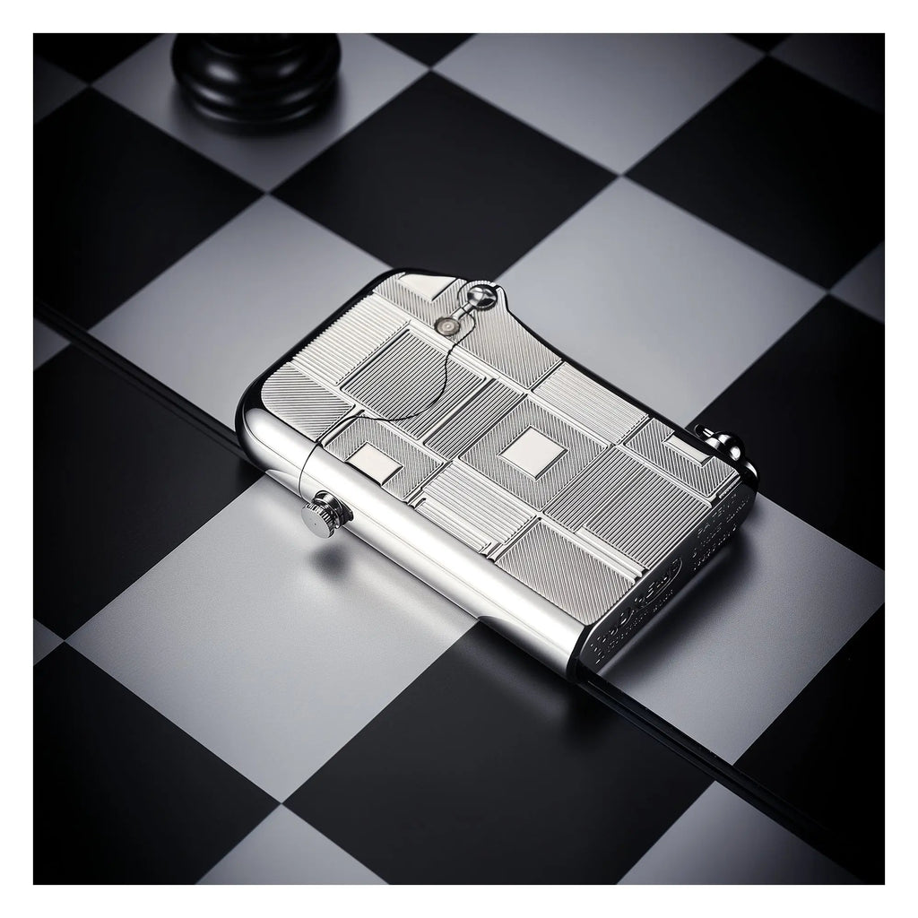 A Thorens Single Claw Gen 1 lighter featuring a precision-engraved geometric pattern and silver finish, resting on a black and white chessboard for a sophisticated EDC display.
