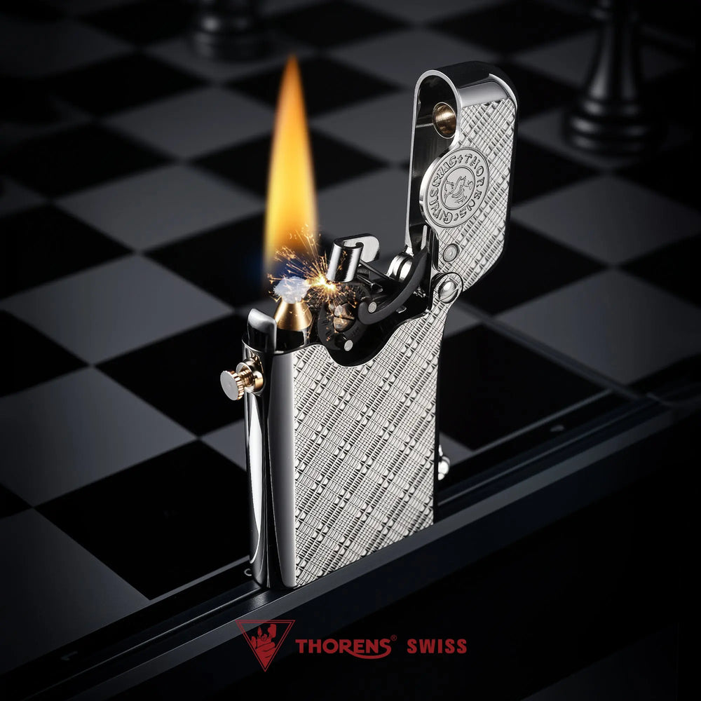 A silver Thorens Gen 1 single claw lighter ignited with a steady flame and sparks, showcasing the plum pattern engraving on a black and white chessboard.