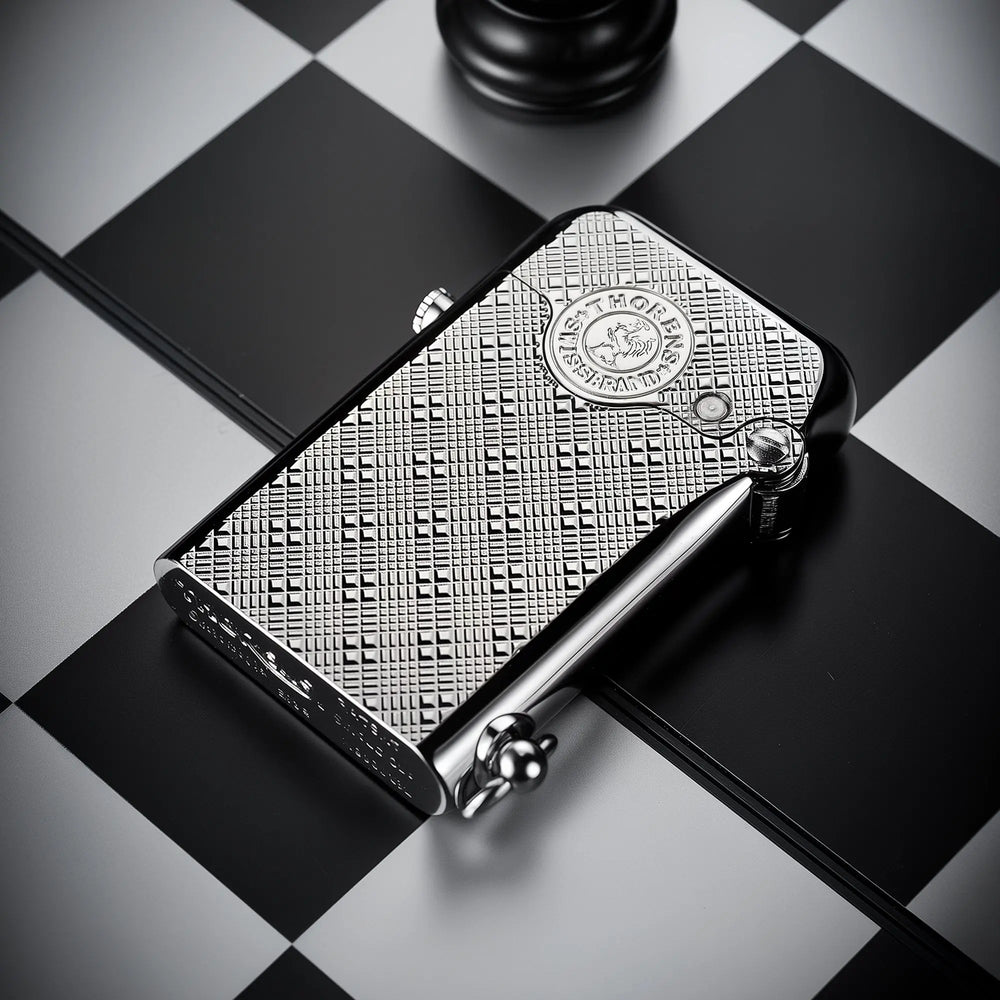 A silver Thorens Gen 1 single claw lighter with an engraved plum pattern lying on a black and white chessboard, showcasing its refined EDC aesthetics.
