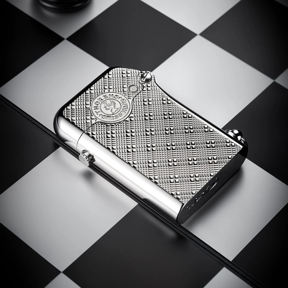 A silver Thorens Gen 1 single claw lighter featuring a detailed plum pattern engraving, resting horizontally on a black and white chessboard.