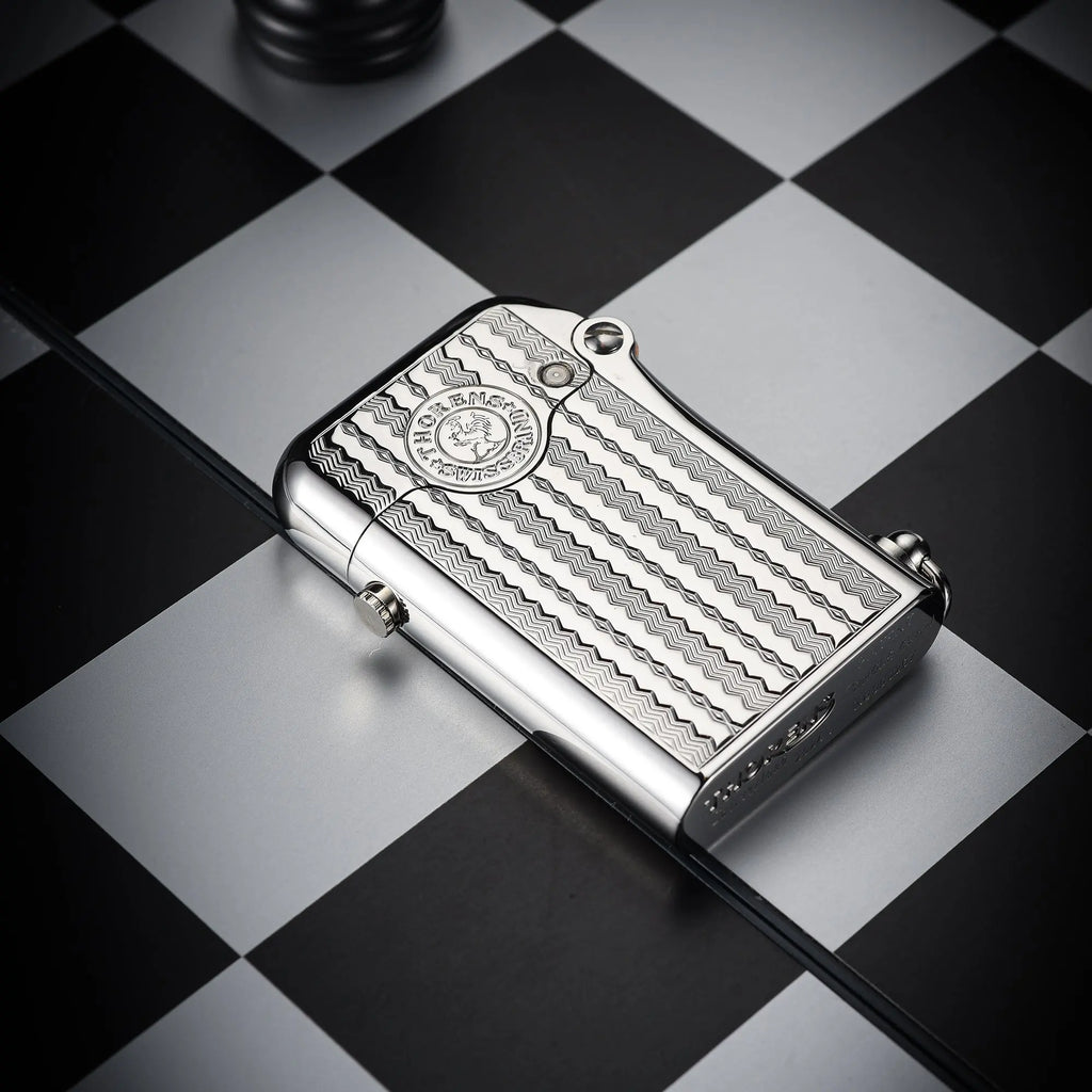 A silver Gen 1 Single Claw lighter featuring an engraved water ripple pattern and heritage brand emblem, resting on a monochrome chessboard.