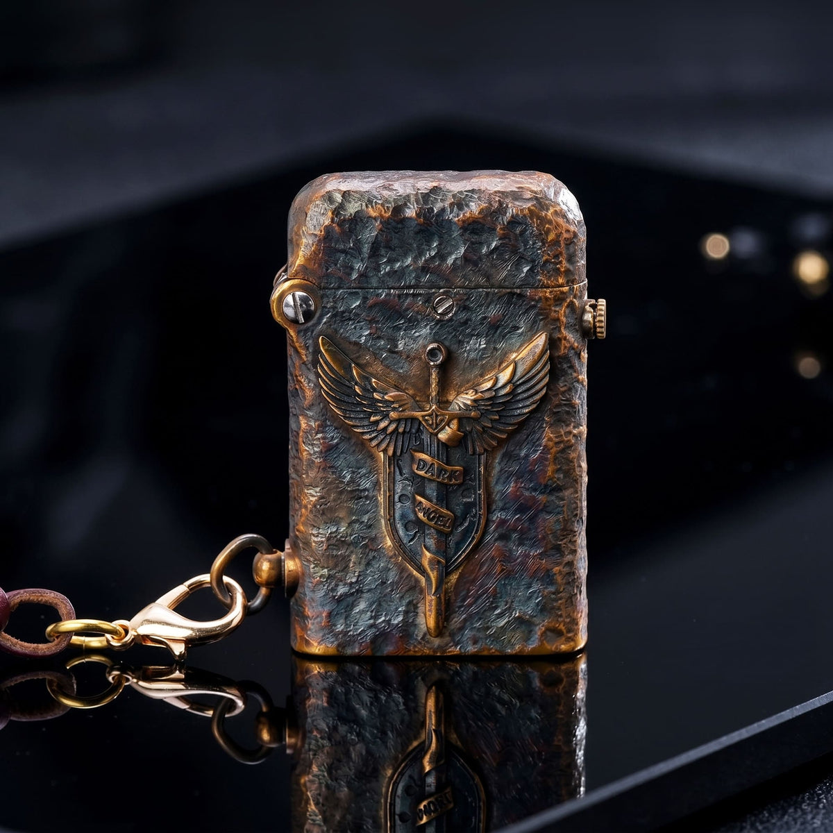 Thorens Gen 2 Double Claw Dark Angel Blade lighter shown closed on a glossy black surface, highlighting the winged blade emblem, distressed brass finish, and side leather charm.