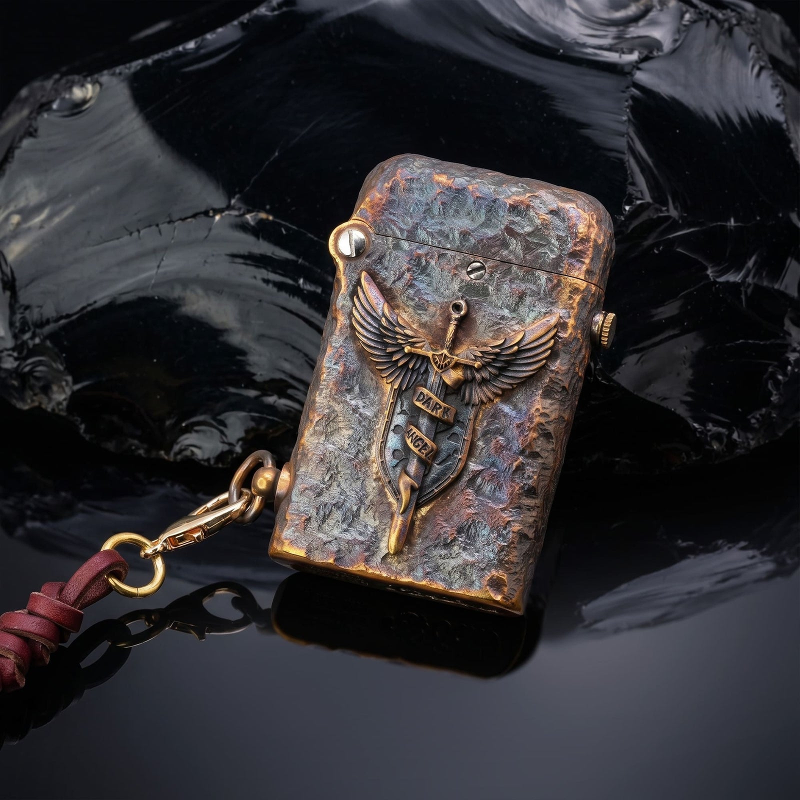 Thorens Gen 2 Double Claw Dark Angel Blade lighter shown closed with raised winged blade emblem, distressed brass texture, and side leather charm.