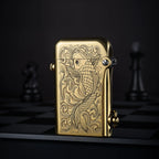 Polished brass Thorens Gen 2 double claw lighter with a detailed koi fish engraving, standing upright against a dark chessboard backdrop.