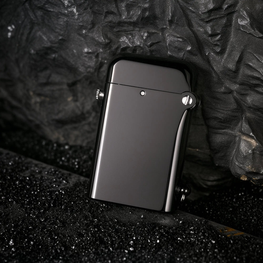 A glossy black Gen 2 Double Claw lighter leaning against a dark, textured rock surface, highlighting the sleek contrast between its polished finish and the rugged outdoor background.