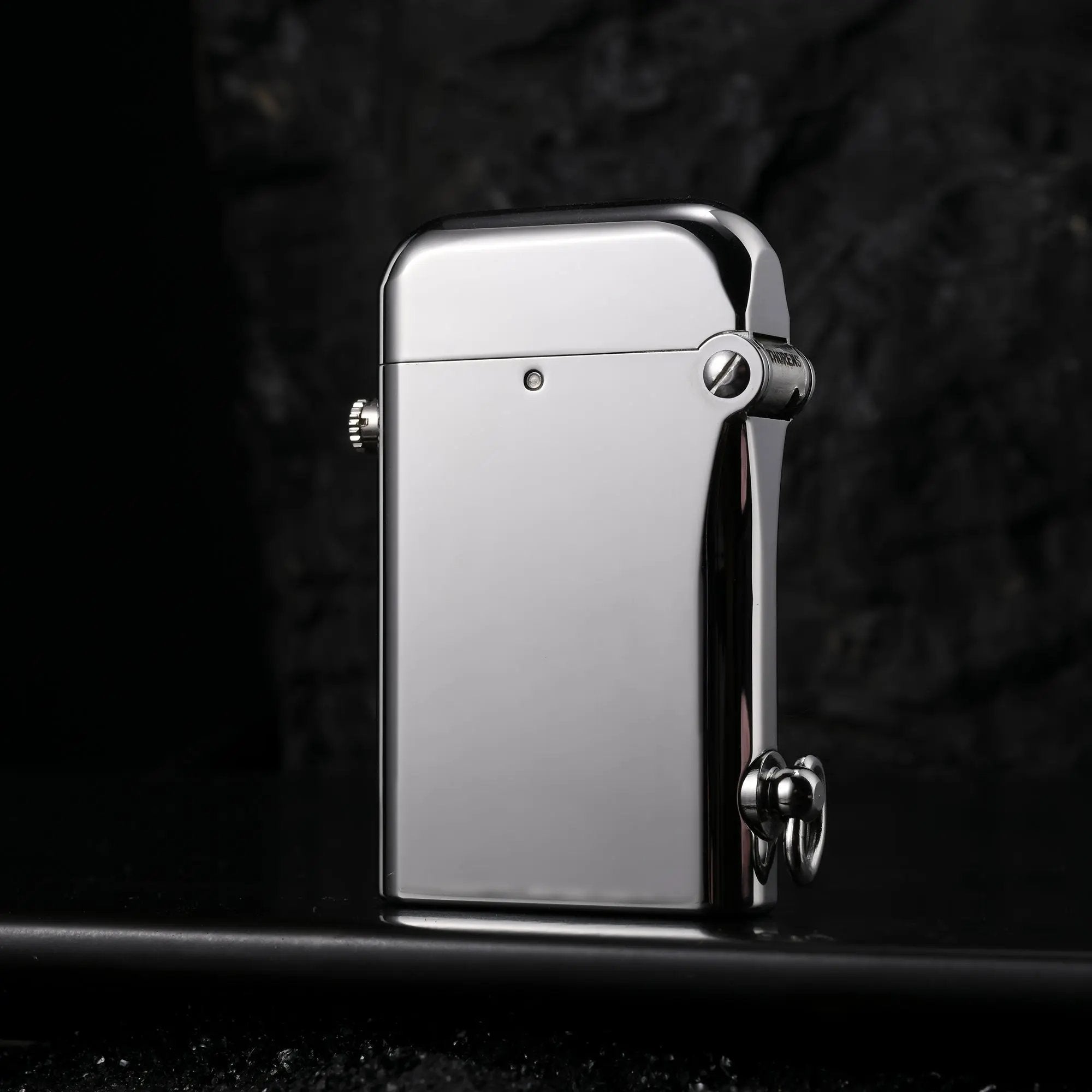 A Thorens Gen 2 Double Claw silver lighter with a mirror-polished glossy finish, standing against a dark stone background with a sleek reflection.