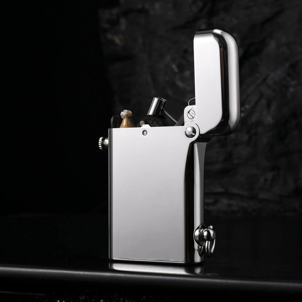 An open Thorens Gen 2 Double Claw silver lighter with a high-gloss finish, showcasing its internal mechanical structure against a dark, textured background.