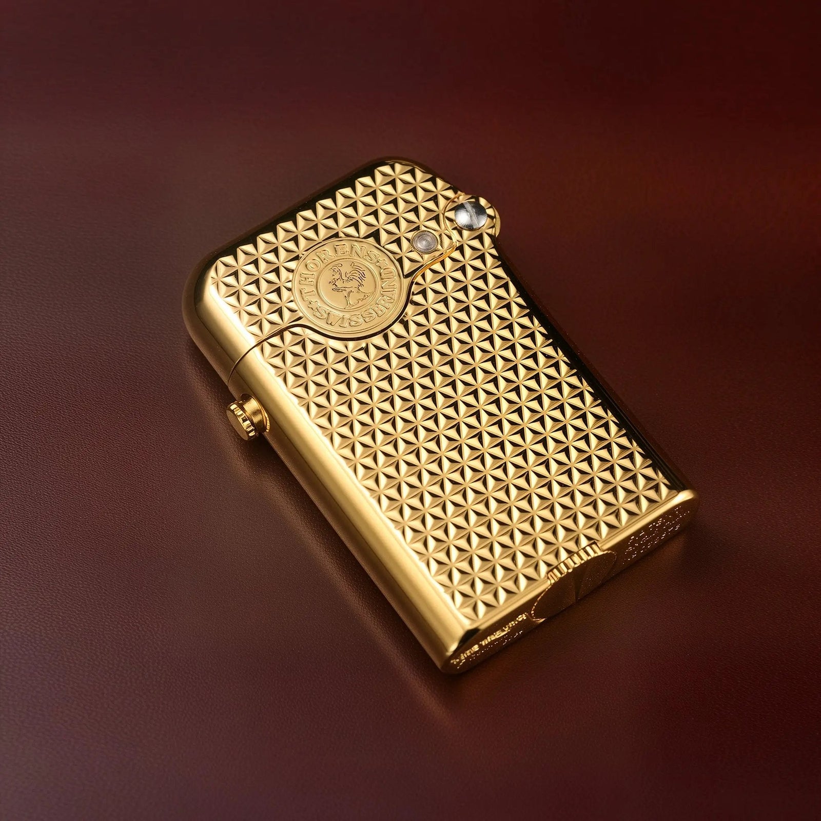 A Thorens Gen 3 gold lighter resting on a leather surface, highlighting the precision-engraved diamond grid texture and signature mechanical hinge.