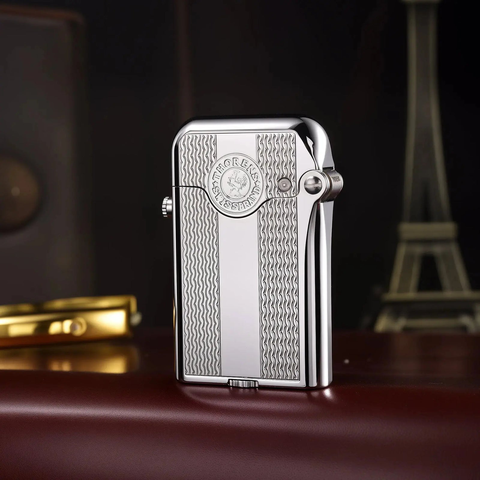 A silver-finished Thorens Gen 3 single claw lighter resting on brown leather, showcasing the high-polish finish and the "Patent Single Claw" bottom engraving.
