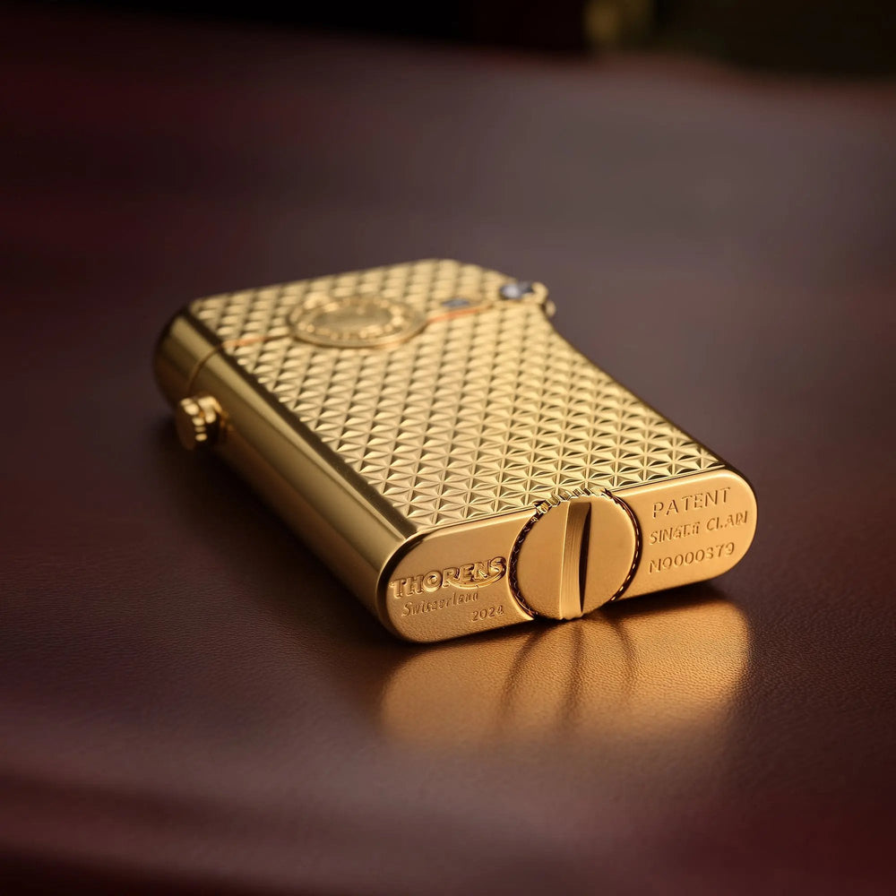 A detailed view of the bottom of a gold Thorens Gen 3 Diamond Grid lighter, showing the authentic Swiss heritage engraving and patent details.