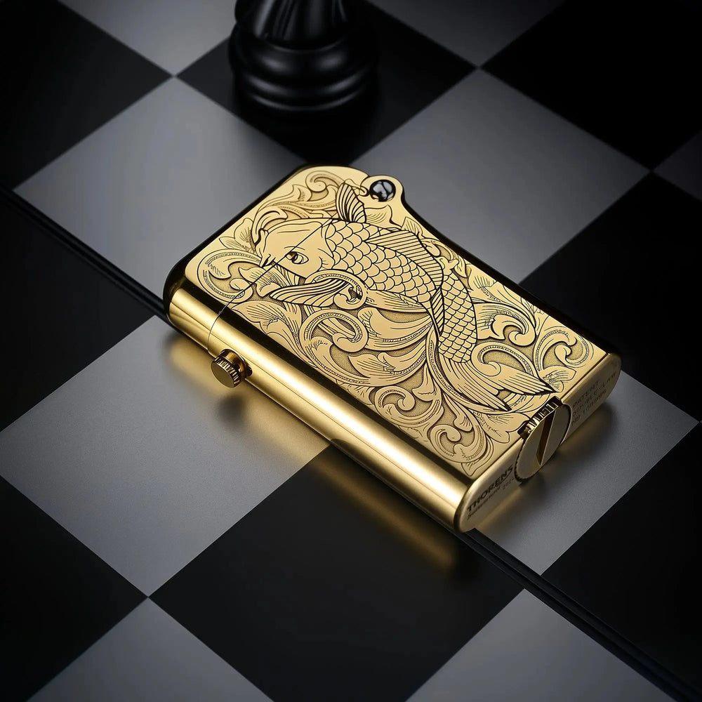 Thorens Gen 4 Double Claw lighter in a brass finish with an engraved koi pattern, photographed on a black and gray checkered surface in an angled close-up view
