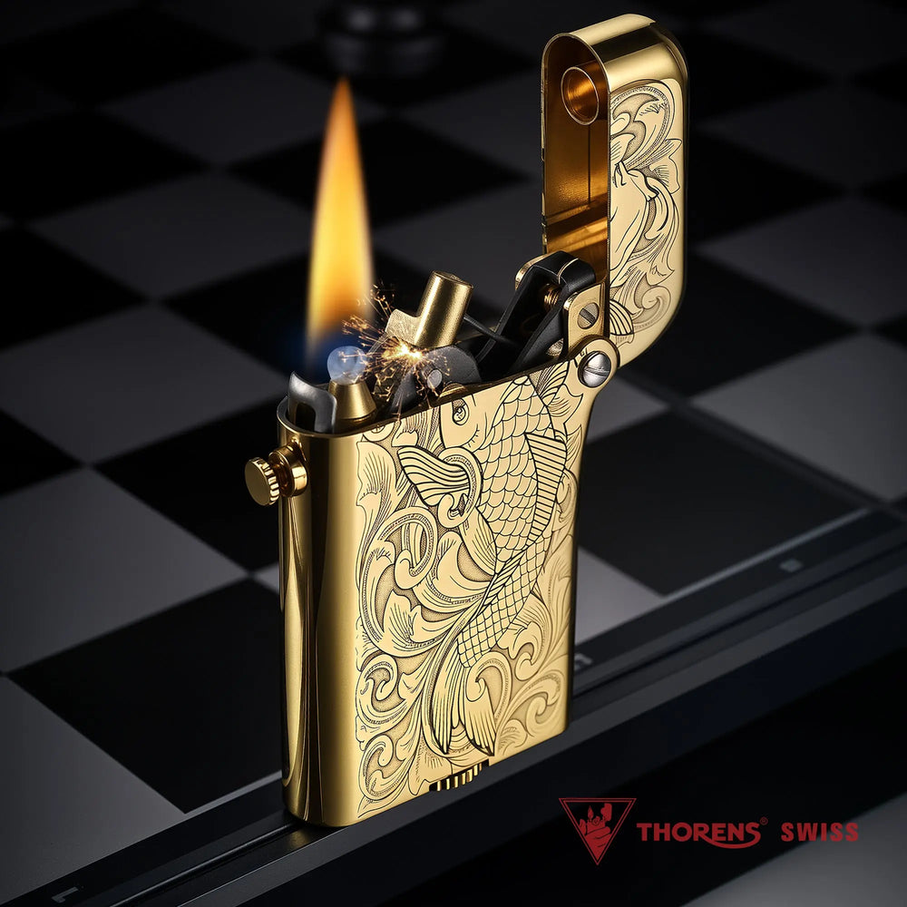 A brass Thorens Gen 4 double claw lighter in action, showing the ignited flame and internal mechanical sparks against an engraved koi fish pattern.