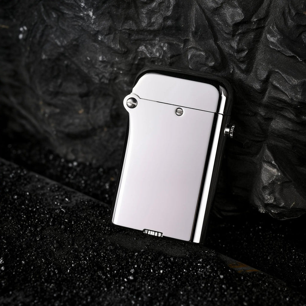 Thorens Gen 4 double-claw lighter with a high-gloss silver mirror finish, leaning against a dark, volcanic rock textured background.