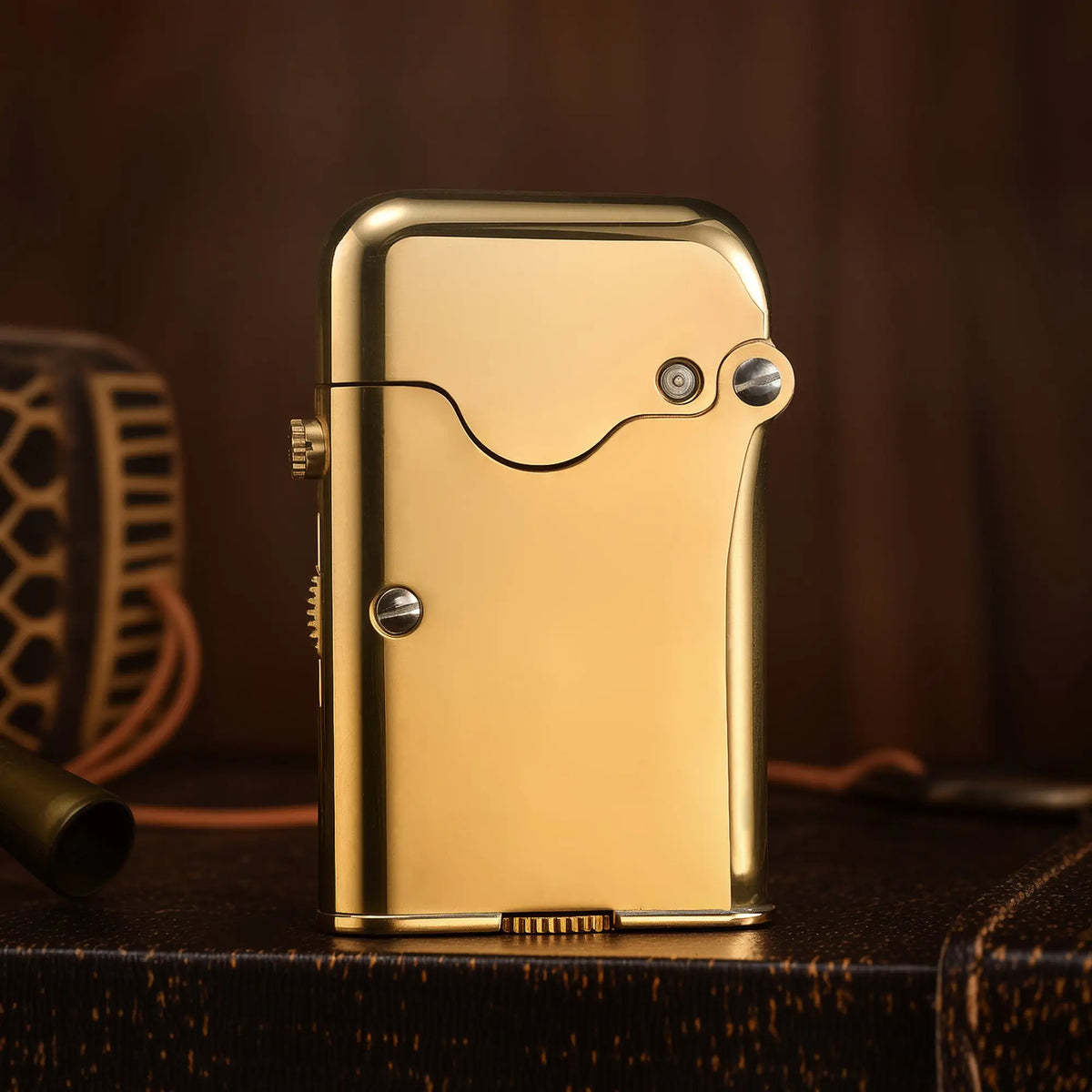 A glossy brass Thorens Gen 7 TELEFLAM lighter standing on a dark wooden surface, showcasing its refined metallic finish and single claw mechanical structure.