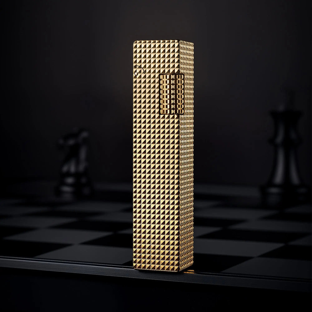 Gold small square textured Thorens side-slip rectangular lighter standing upright on a dark checkerboard surface