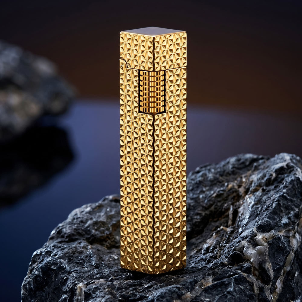 Thorens rectangular lighter with gold starburst pattern shown closed and upright on dark stone, highlighting the raised surface pattern and side ignition wheel.