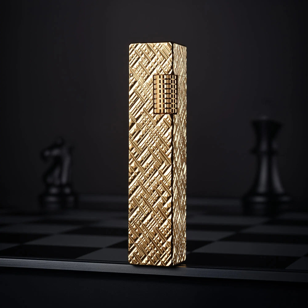Gold carved rectangular Thorens side-slip lighter standing upright on a dark checkerboard surface