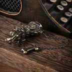 An antique brass Thorens lighter sculpted in the shape of a Golden Retriever head, featuring a decorative chain and bone charm on a wooden surface.