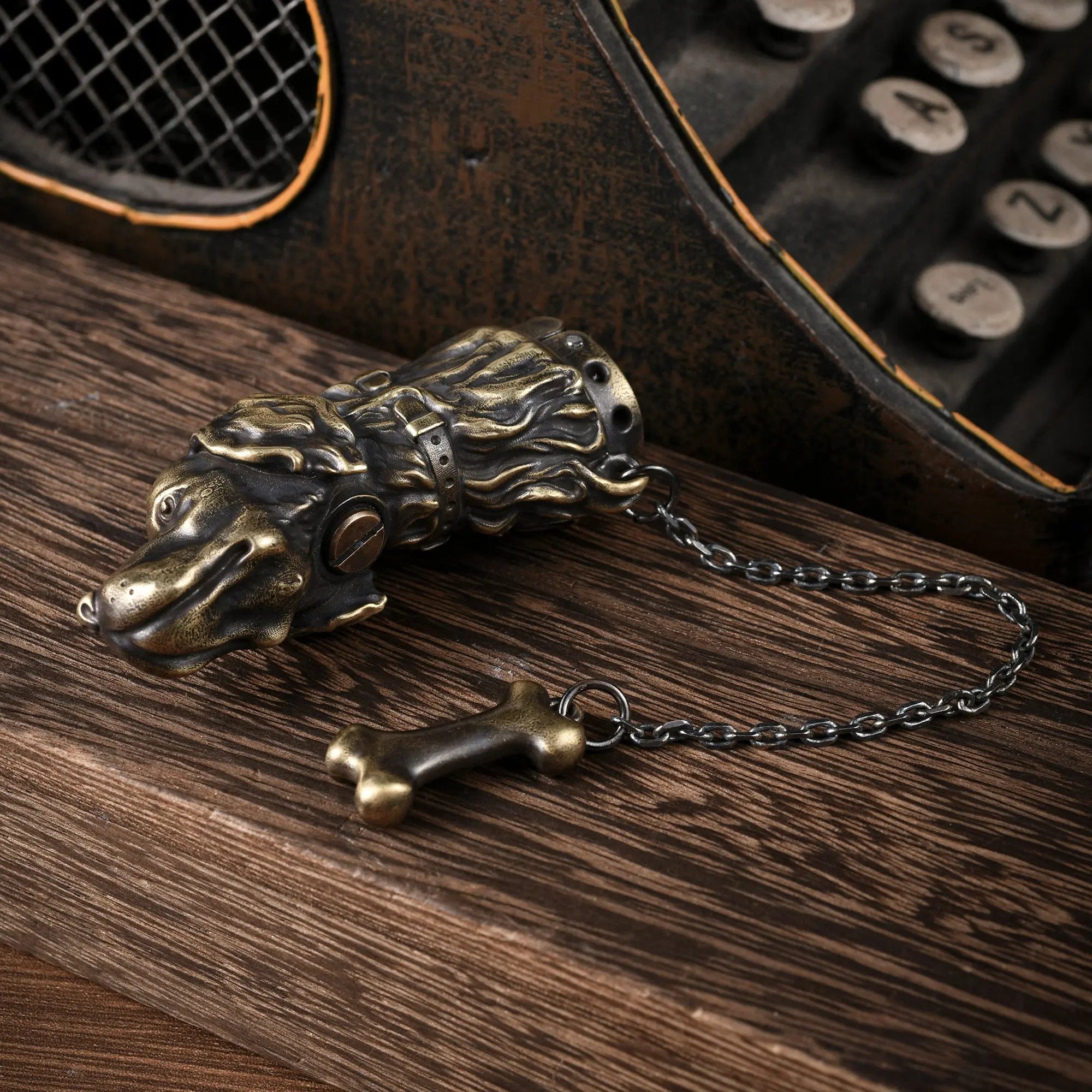 An antique brass Thorens lighter sculpted in the shape of a Golden Retriever head, featuring a decorative chain and bone charm on a wooden surface.