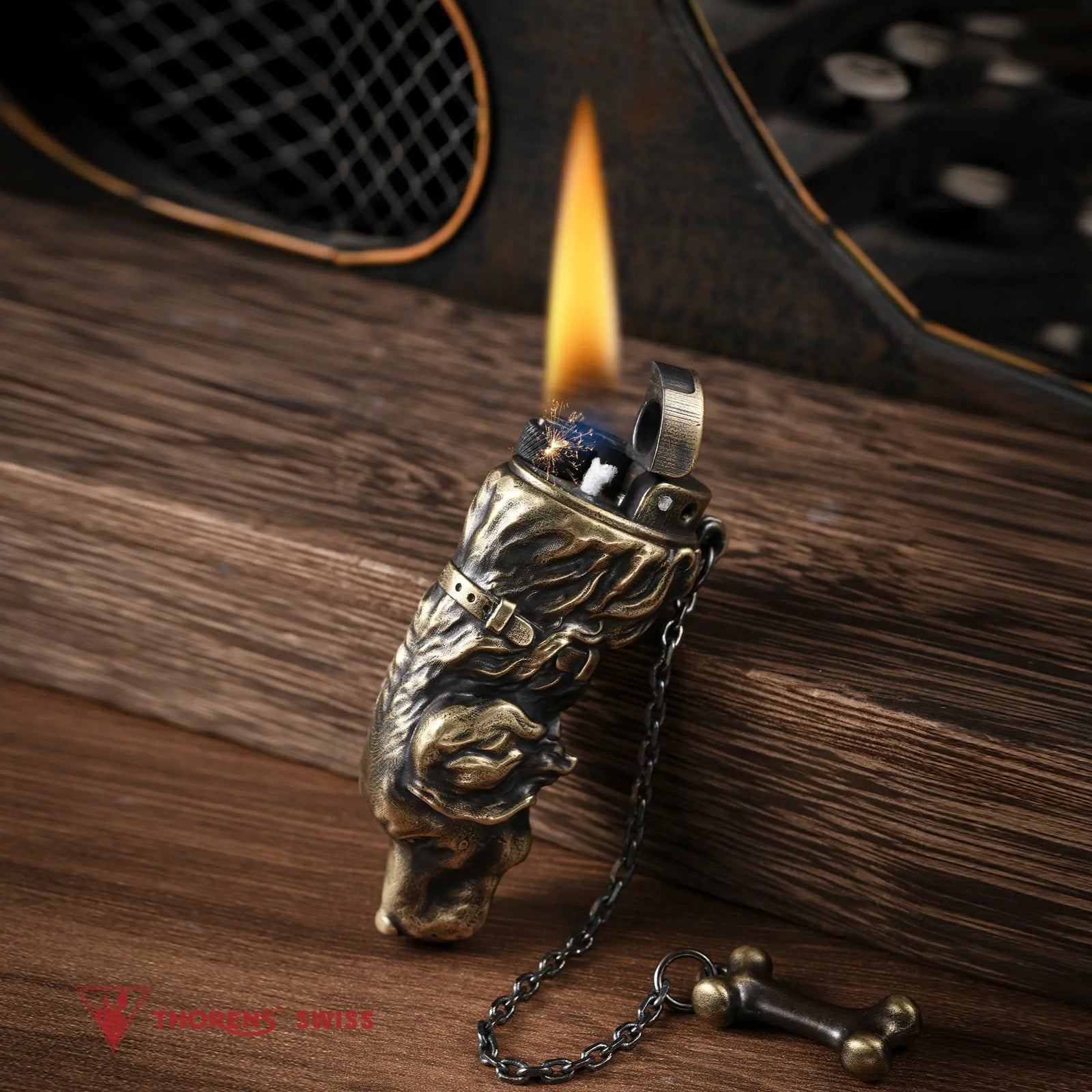An angled close-up of the Thorens Golden Retriever lighter, a detailed, antique brass sculpted dog head with an active flame ignited, resting on rustic wood with its bone charm.