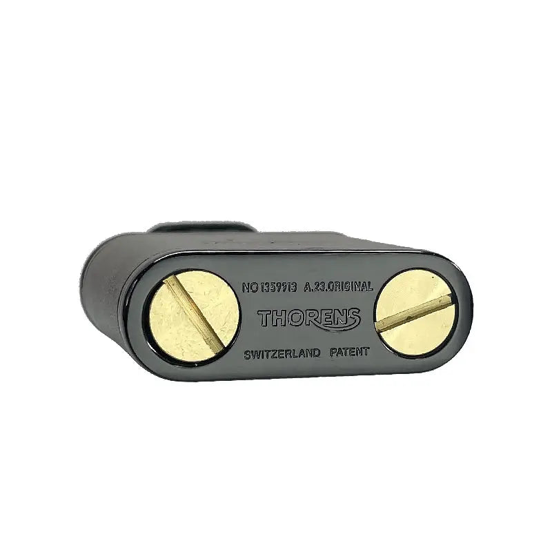 The base of a gray Thorens cowhide lighter featuring two brass fuel screws and authentic "Switzerland Patent" engravings on a matte metal plate.