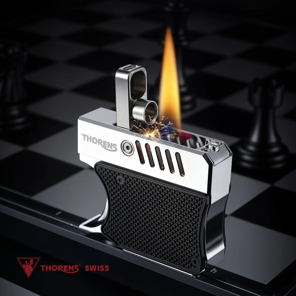 A Thorens Gun Lighter in black and silver shown during ignition on a chessboard. The image captures the mechanical arm flipped up, a bright flint spark, and a steady flame emerging from the top.