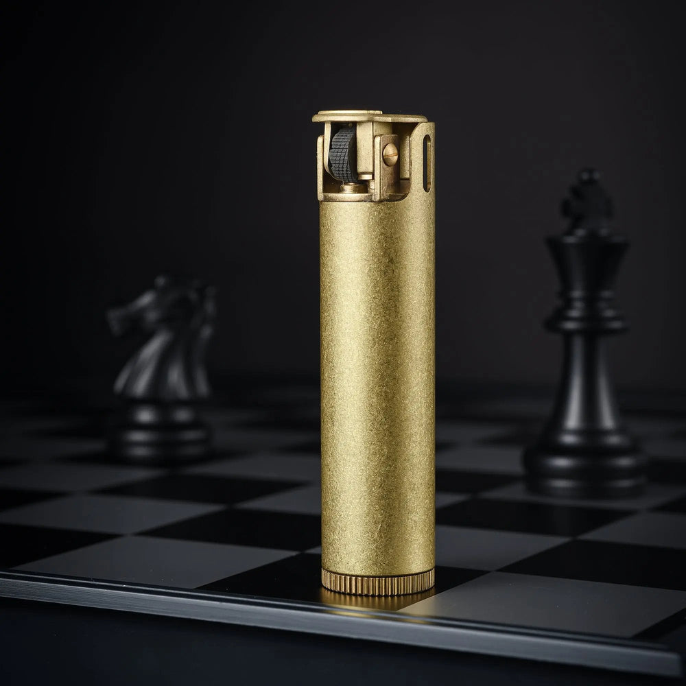 Close-up of an Ignis Tower brass lighter on a chessboard, focusing on the textured mechanical flint wheel and the robust pillar-style windguard.