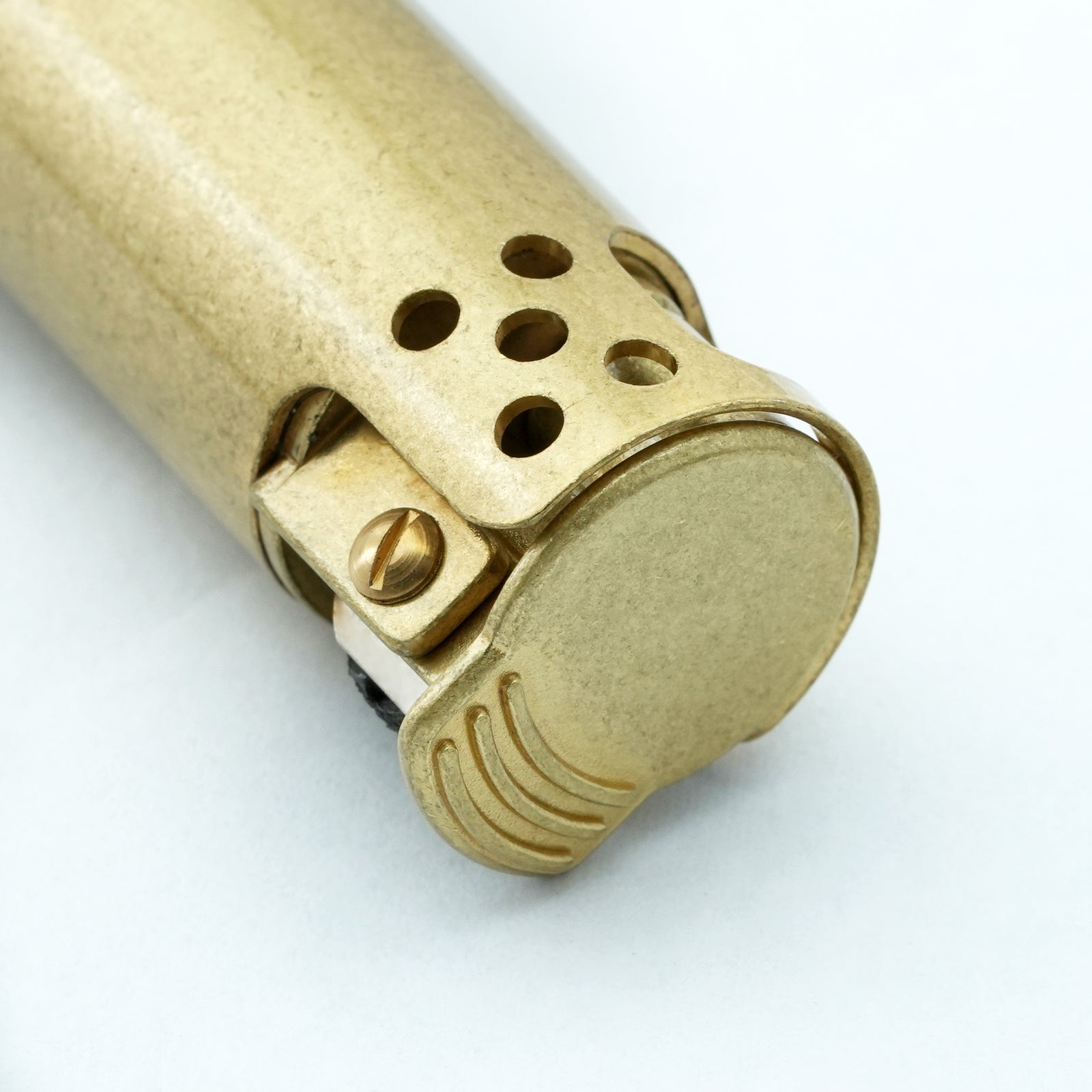 Close-up of an Ignis Tower brass lighter on a chessboard, focusing on the textured mechanical flint wheel and the robust pillar-style windguard.