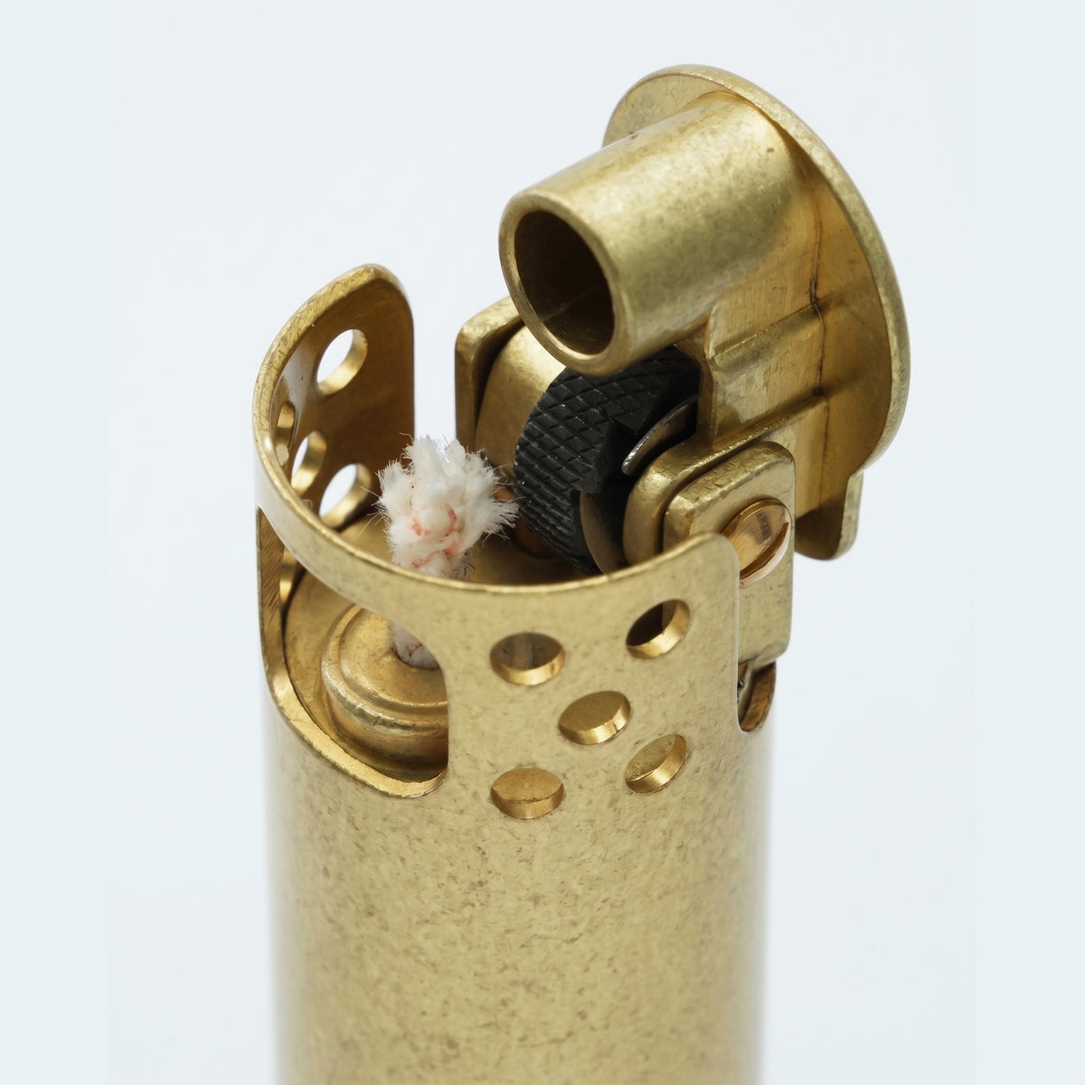 A brushed brass Ignis Tower lighter resting at an angle on a dark surface, with a black and white chessboard blurred in the background.