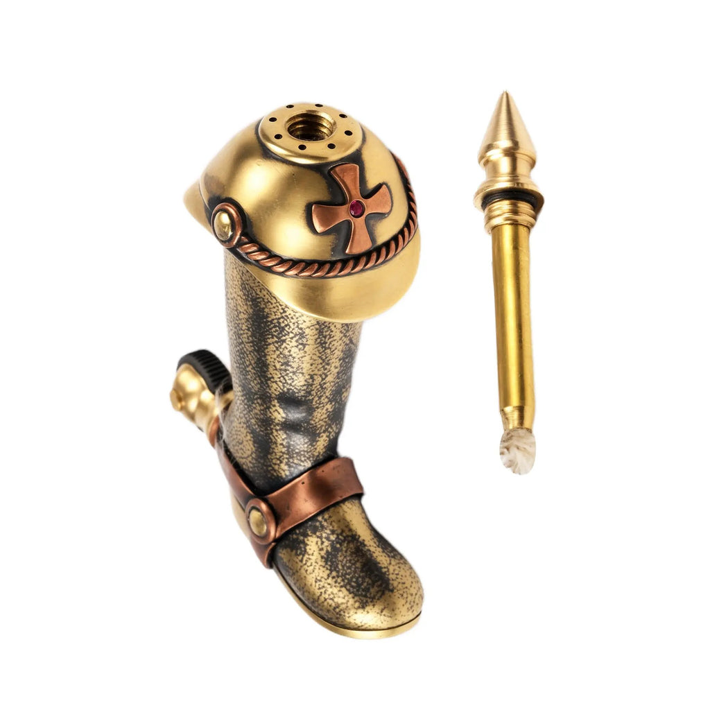 A high-resolution photo of the Knight's Boot permanent match lighter on a pure white background, showing the boot-shaped fuel tank with a cross emblem and the unscrewed brass striking rod.