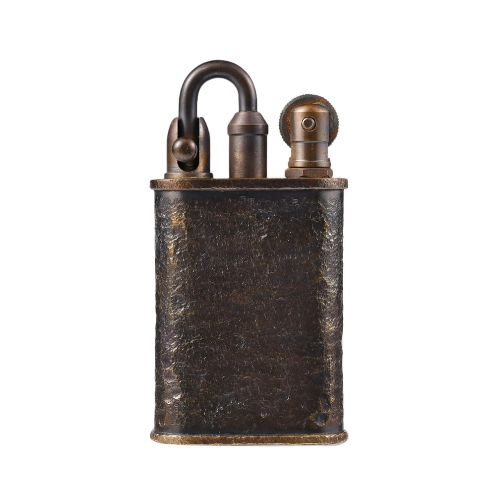 A Thorens Lockflame lighter featuring a rugged hand-carved meteorite crater texture on an antique brass body with a signature locking arm mechanism.