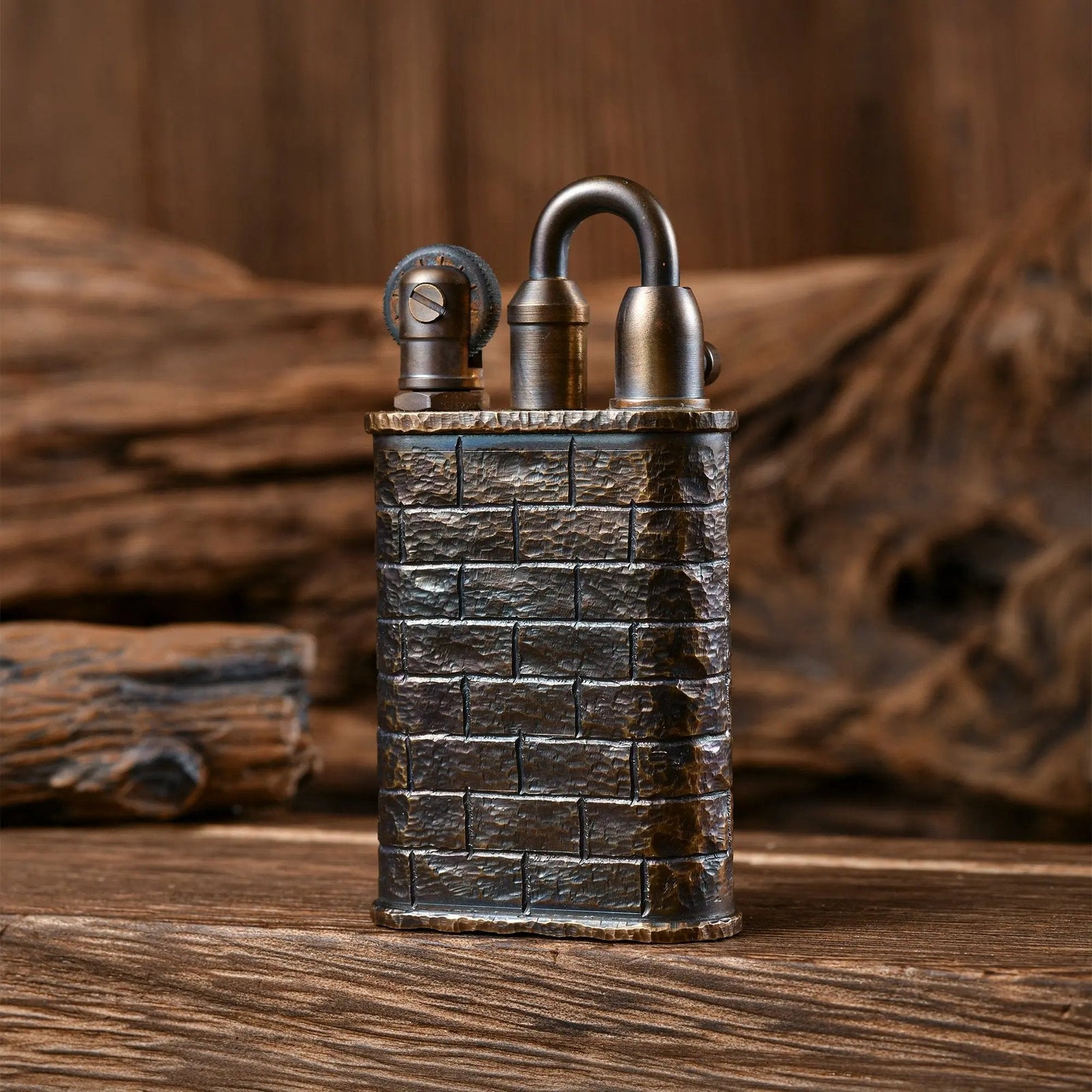 A Thorens Lockflame lighter with a hand-carved brick wall pattern in weathered brass, showcasing vintage mechanical precision against a rustic wood backdrop.