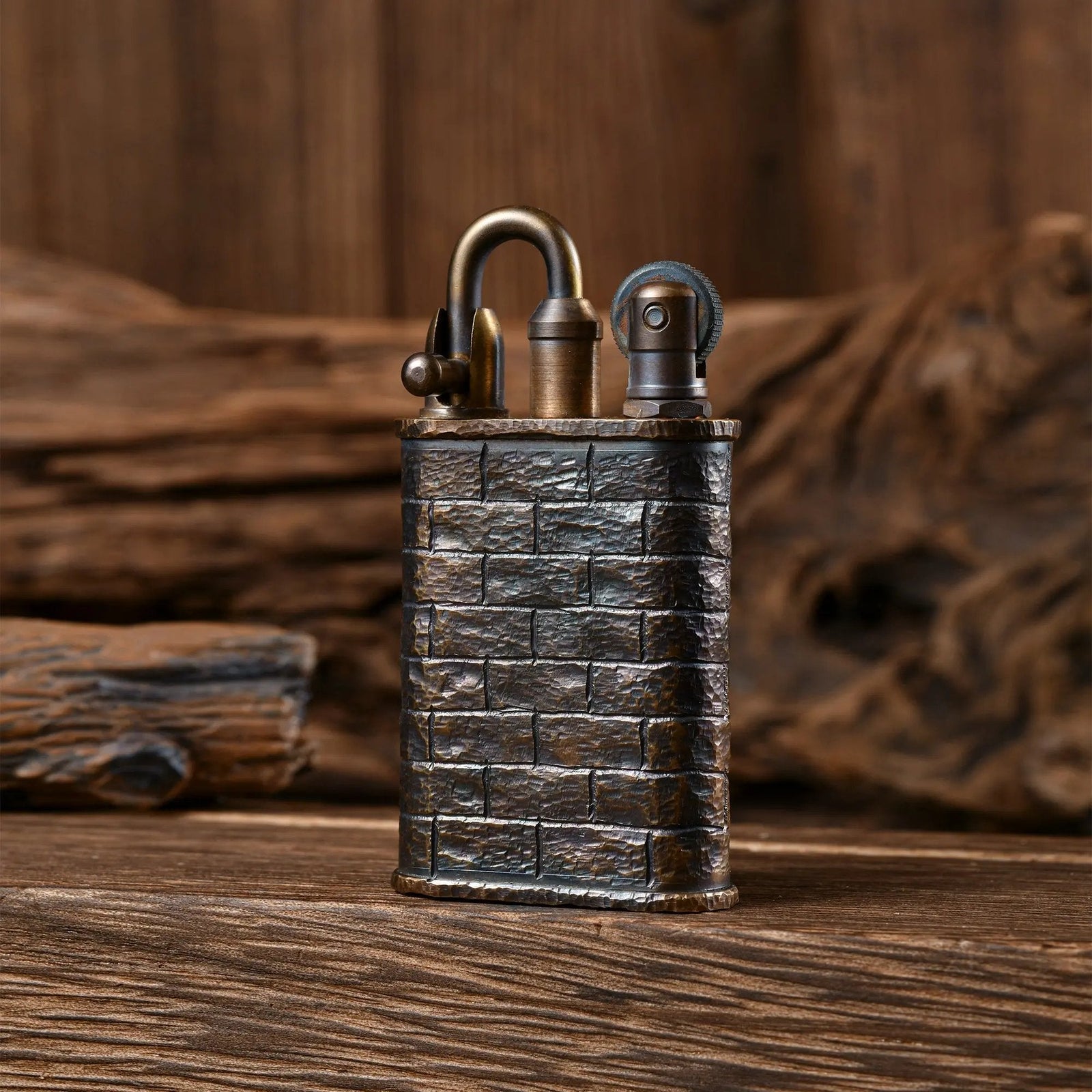 A Thorens Lockflame lighter featuring a hand-carved brick wall pattern on aged brass, standing on a rustic wood surface.