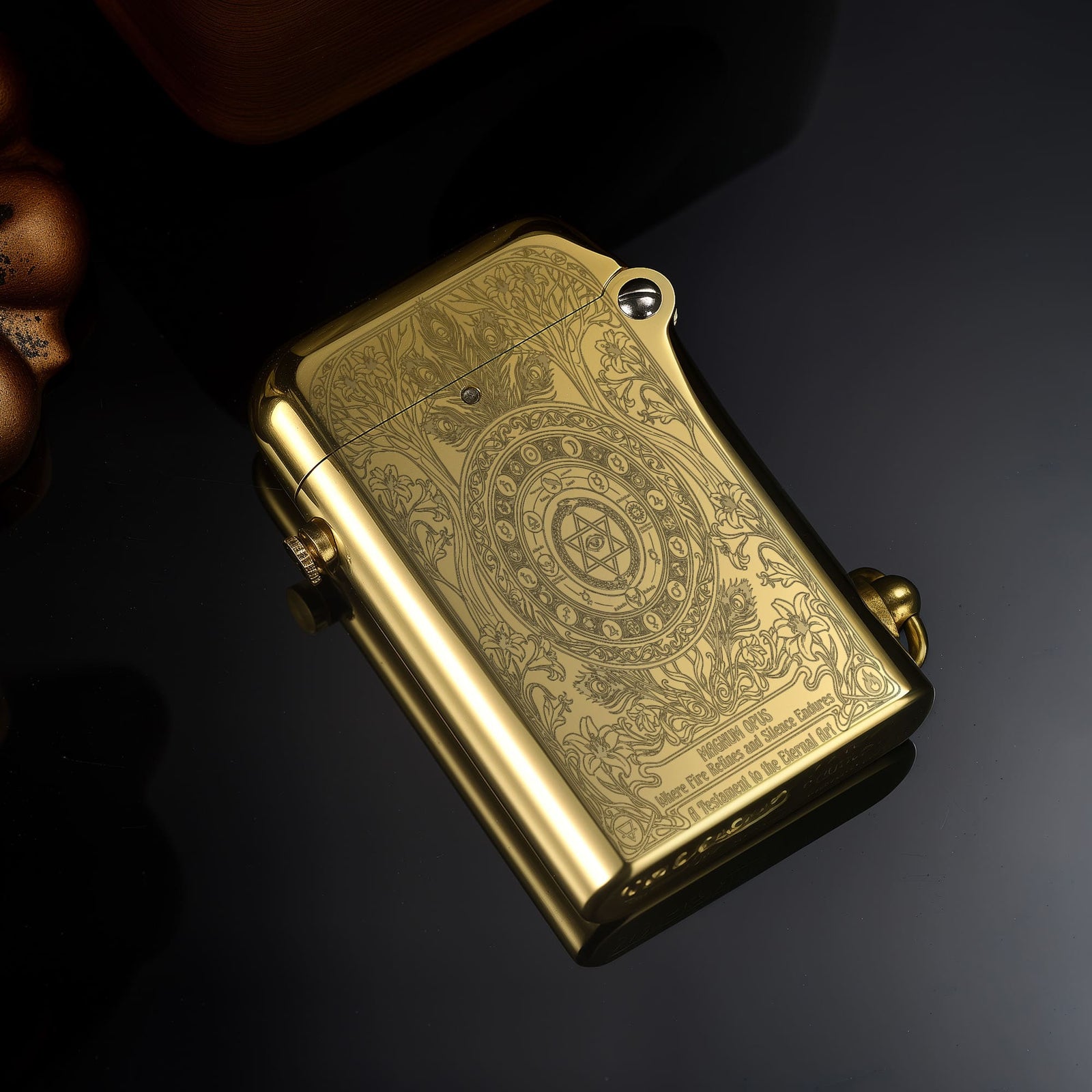 Thorens Magnum Opus lighter in polished brass shown closed, featuring intricate engraved surface patterns and smooth curved edges on a dark reflective background.