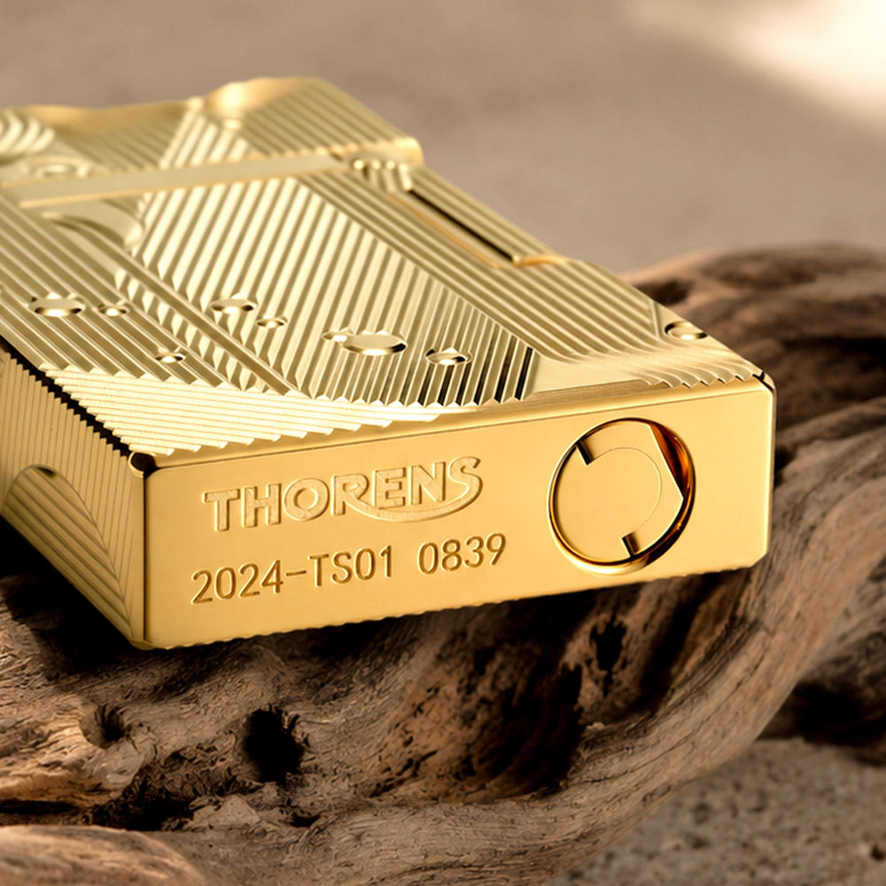 A stunning gold Thorens lighter featuring a highly detailed Art Deco mermaid engraving with flowing lines and bubble accents, set against a dramatic chess-themed background.