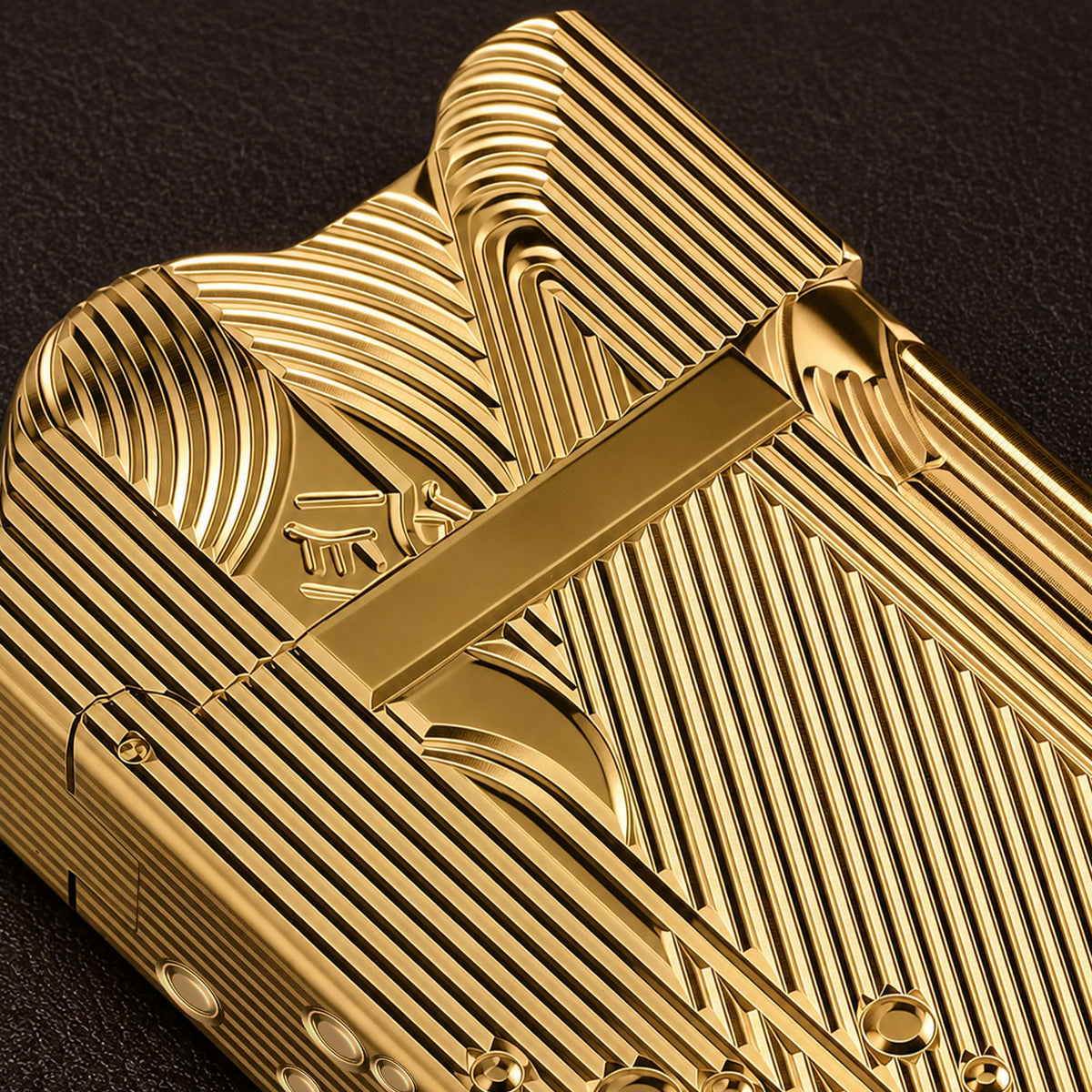 A stunning gold Thorens Mermaid lighter lying on a black and white chessboard, showcasing the intricate linework on its side panels and the unique scalloped top edge.