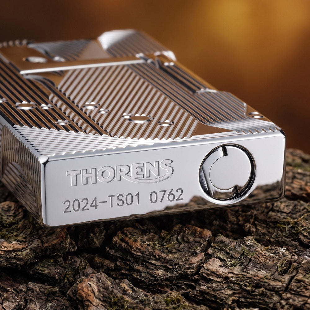 A front-profile view of the silver Thorens Mermaid lighter, showcasing the high-luster chrome finish and intricate Art Deco engravings against a dark, dramatic background.
