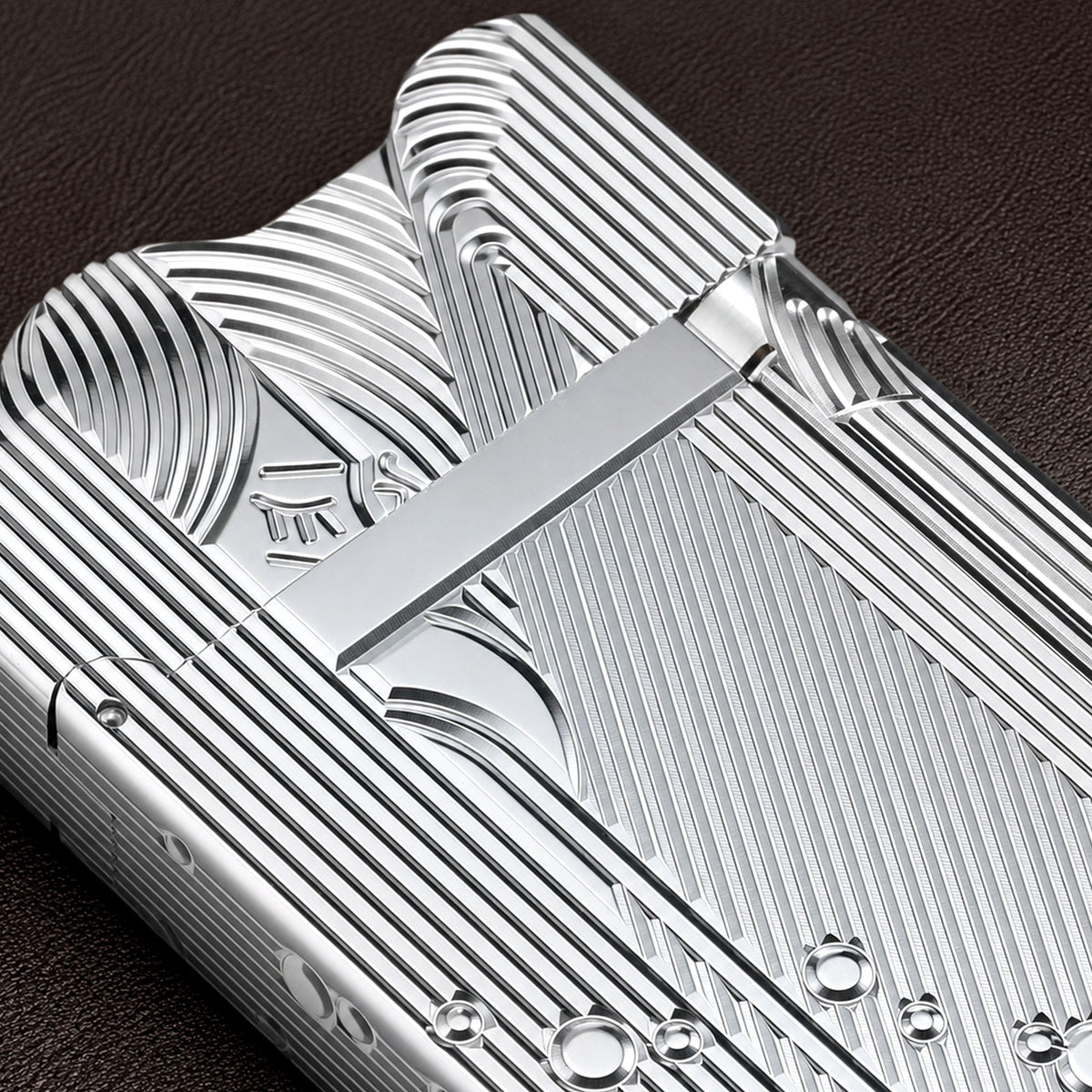 A silver Thorens Mermaid lighter resting on a chessboard, showing the intricate linework on its side panels and the unique scalloped top edge in a bright, metallic finish.